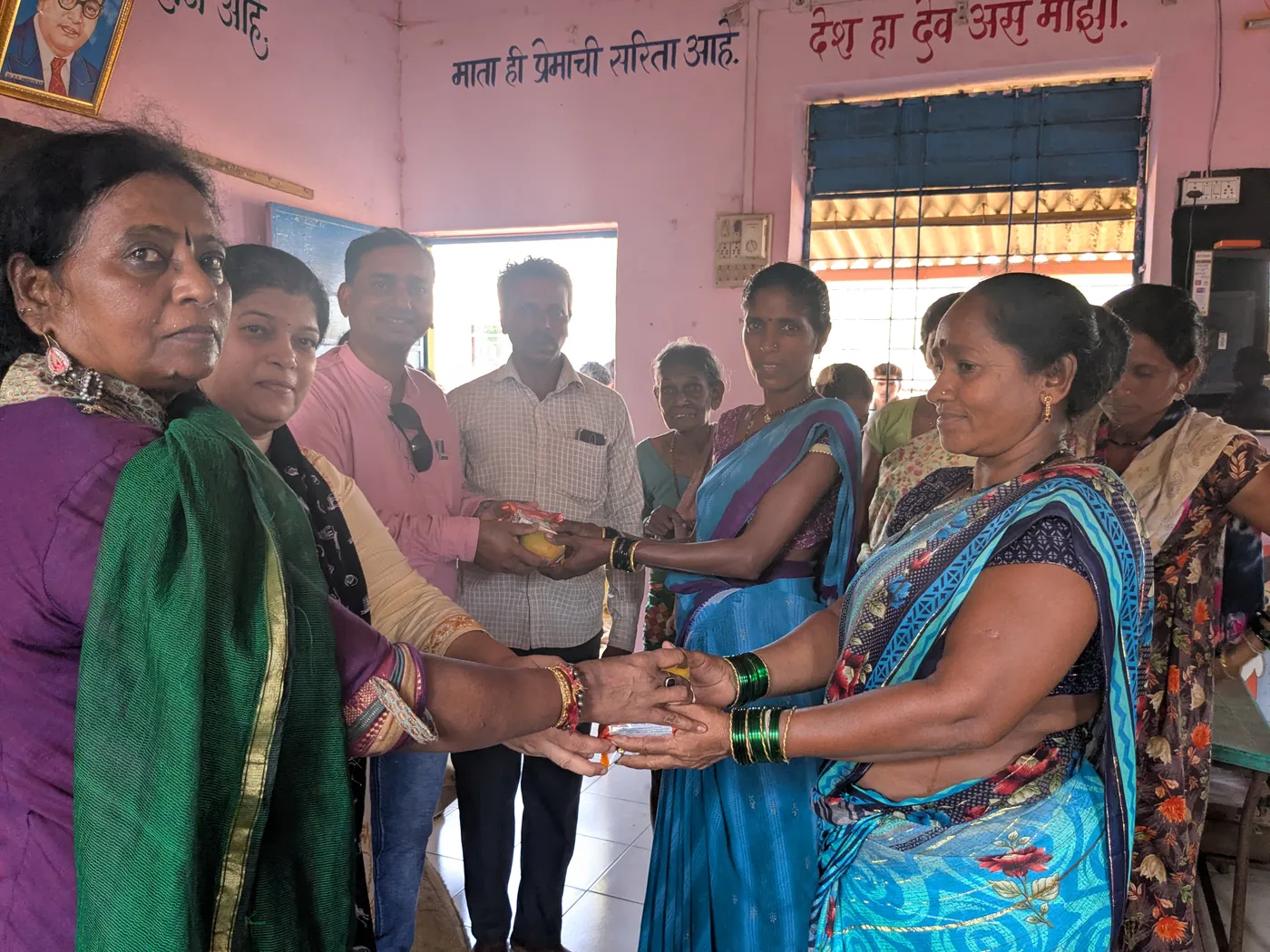 A HariKshama Foundation volunteer handing treats to women at the Nifarwadi hamlet